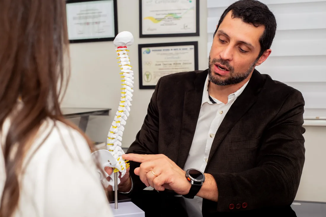 Dr. José Carlos explicando a uma paciente, com apoio de um modelo de coluna, de onde vem a dor